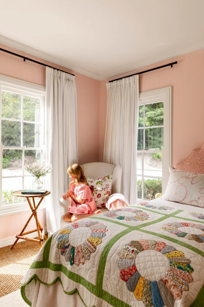 Girl's bedroom with child sitting in armchair at window