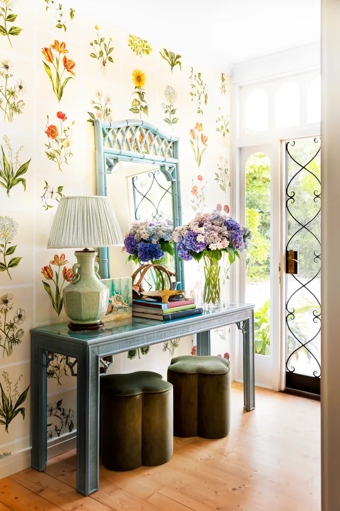 Entry with floral wallpaper and mirror with lamp on blue sideboard