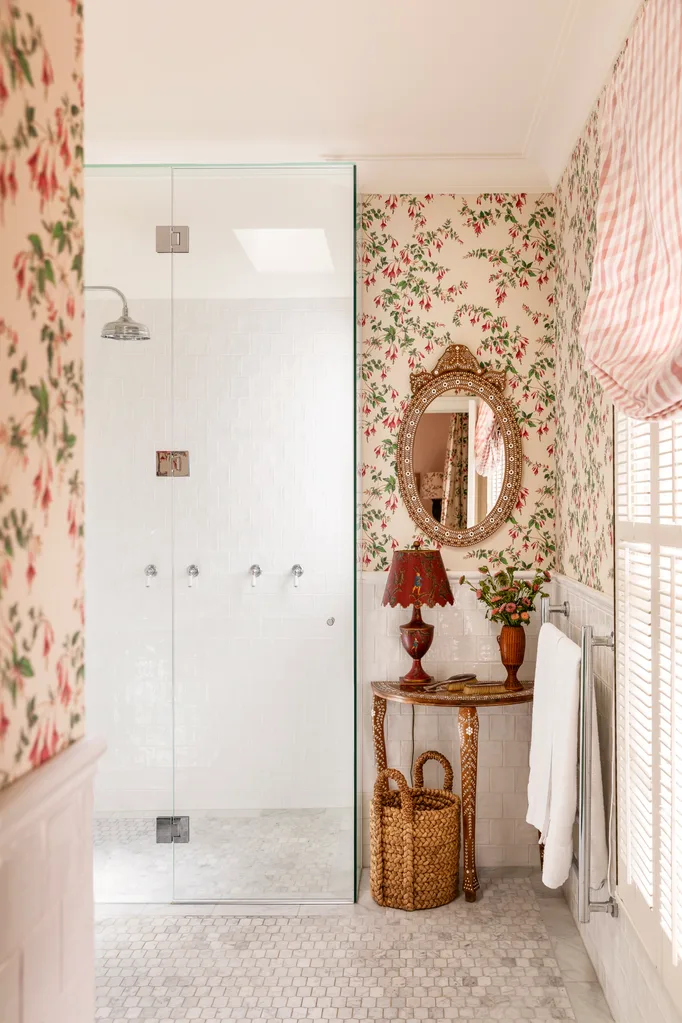 Ensuite with pretty wallpaper, oval mirror and lamp next to shower