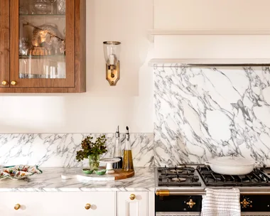 Close up of kitchen marble splashback with wall light in gold and timber cabinet
