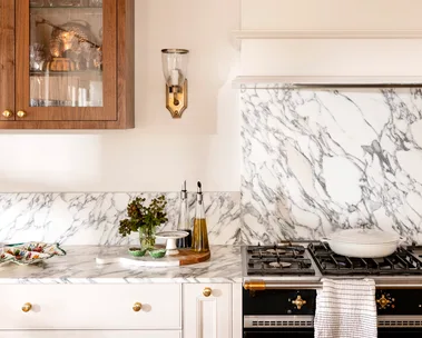 Close up of kitchen marble splashback with wall light in gold and timber cabinet