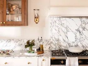 Close up of kitchen marble splashback with wall light in gold and timber cabinet
