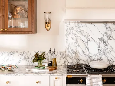 Close up of kitchen marble splashback with wall light in gold and timber cabinet