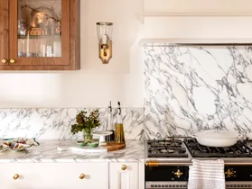 Close up of kitchen marble splashback with wall light in gold and timber cabinet