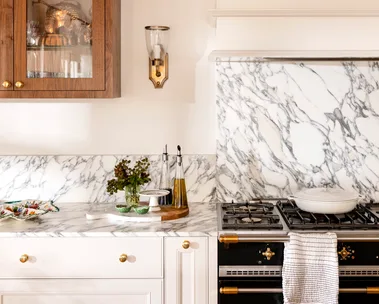 Close up of kitchen marble splashback with wall light in gold and timber cabinet