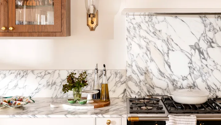 Close up of kitchen marble splashback with wall light in gold and timber cabinet