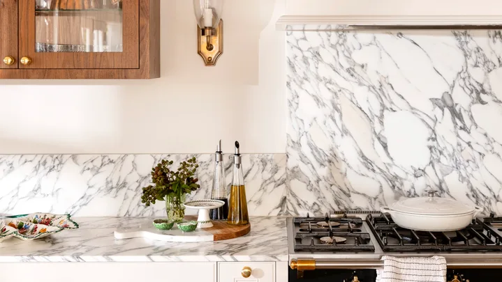 Close up of kitchen marble splashback with wall light in gold and timber cabinet