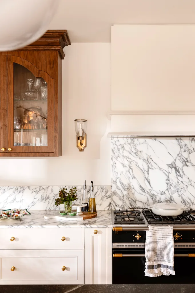 Close up of kitchen marble splashback with wall light in gold and timber cabinet