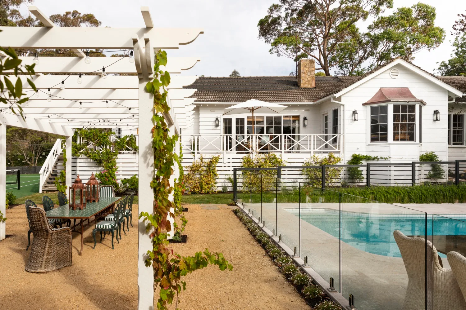 Outdoor pool area and dining table under pergola