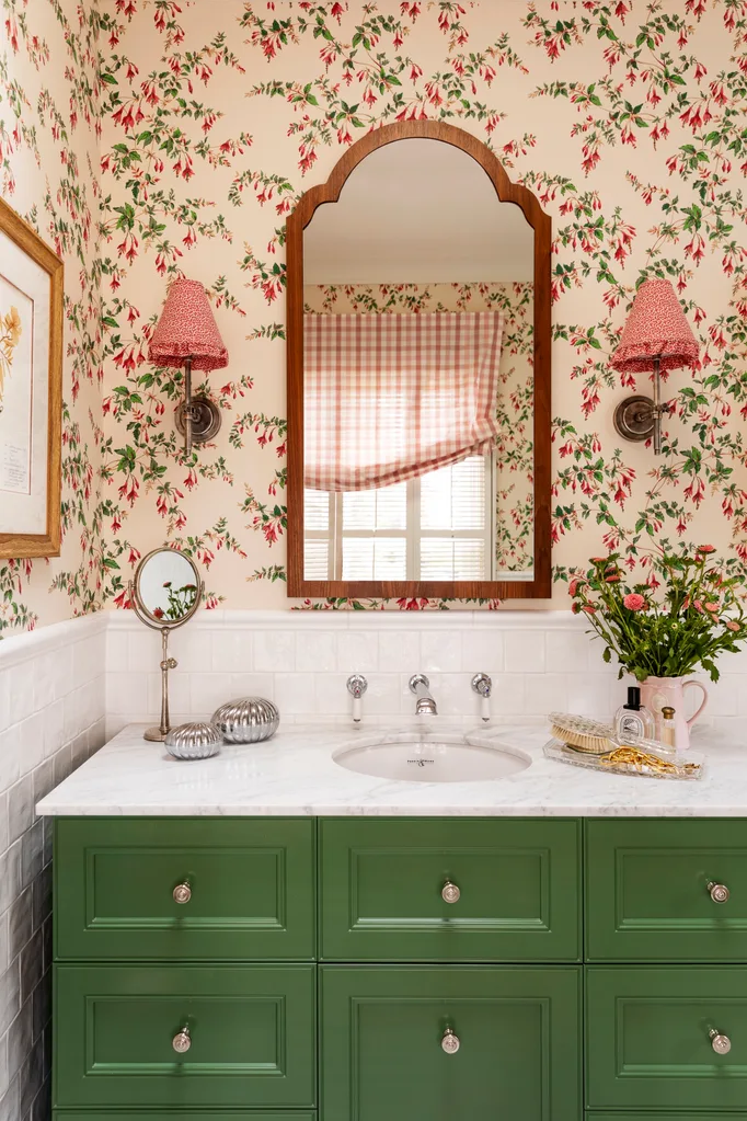 Bathroom vanity with green paint and wall lights on wallpaper