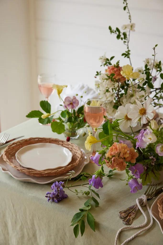 A tablescape or dining setting with a wildflower arrangement, linen tablecloth and ruffled ceramic plates