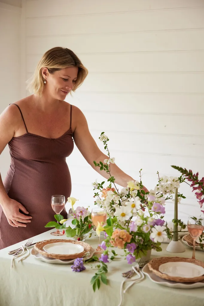 Tanya Barbariol of Oh Flora in Byron Bay with a table arrangement of flowers, linen and ruffled ceramic plates