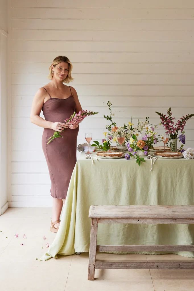 Tanya Barbariol of Oh Flora in Byron Bay with a table arrangement of flowers and linen, plus a rustic bench seat