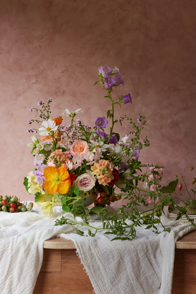 Wildflower arrangement in front of pink textured wall with a linen tablecloth