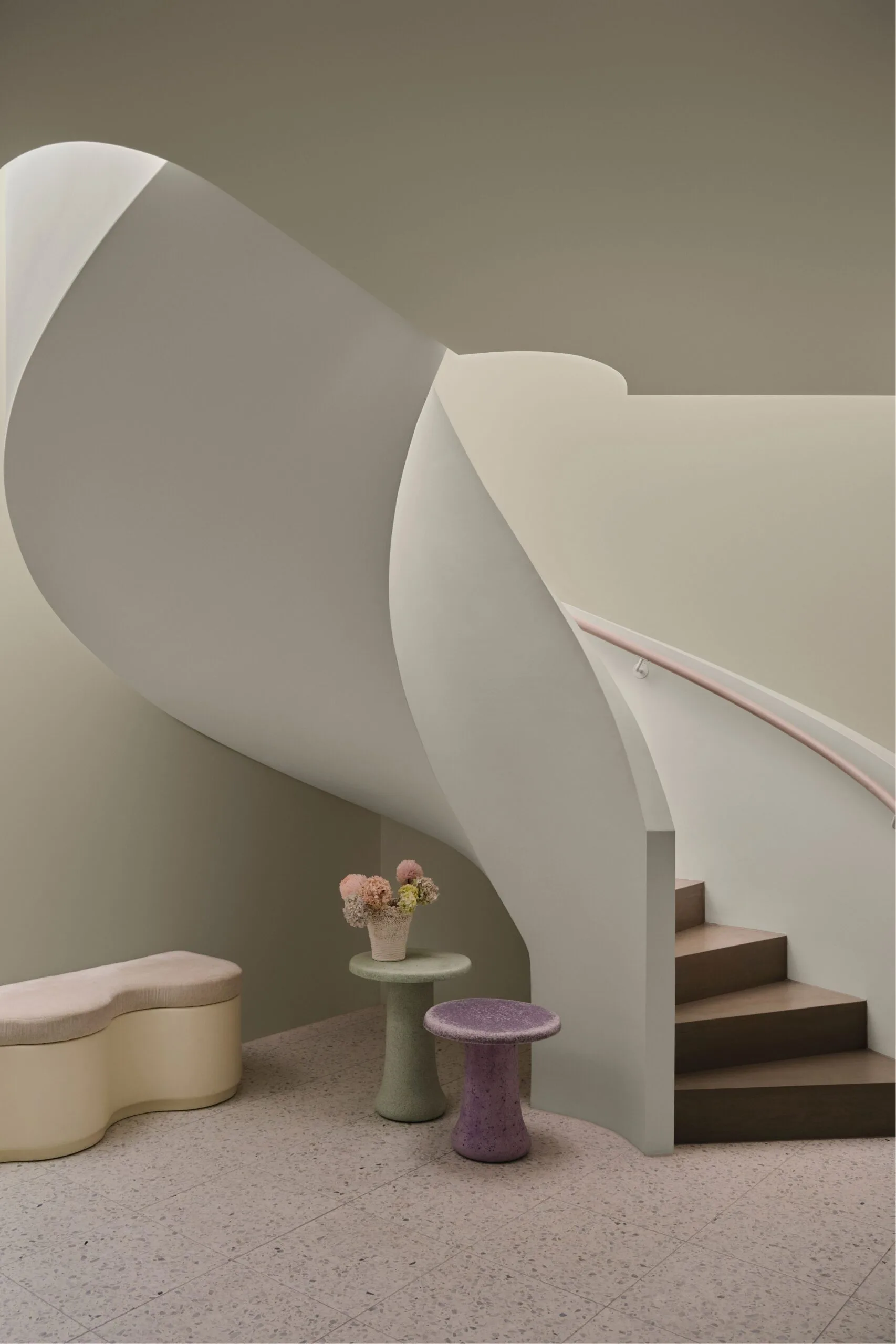 Curved staircase and soft purple and green coloured tables