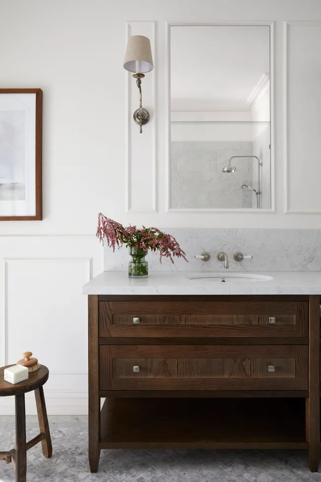 An elevated farmhouse style bathroom with American oak joinery, a marble-topped vanity and rectangular mirror.