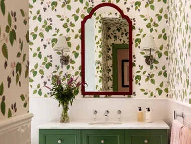 A green bathroom with botanical wallpaper, white tiled wainscoting and green bathroom joinery.