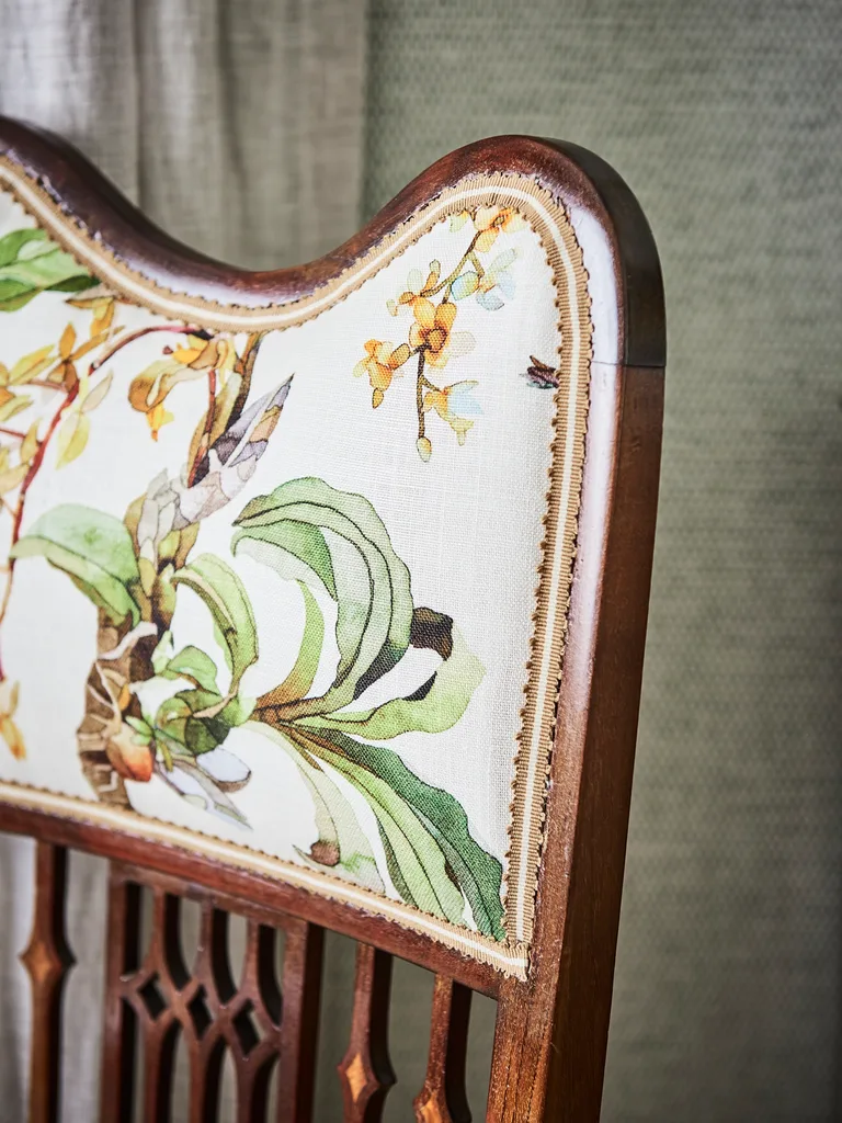 A timber chair with botanical patterned upholstery.