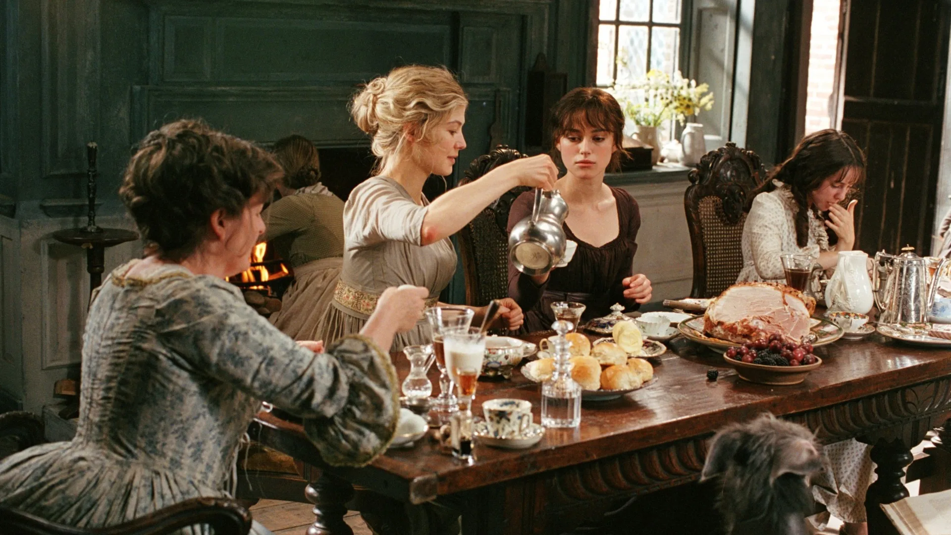 A still from the 2005 Pride and Prejudice movie, with the Bennet sisters and Mrs Bennet gathered around the dining table.