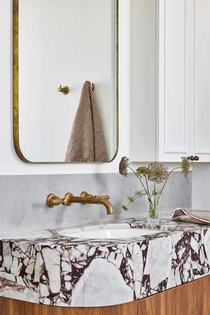 A white bathroom which showcases small bathroom design ideas, such as recessed storage and cabinetry finished in the same shade as the wall for a sleek and unobtrusive appearance.