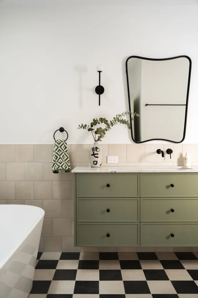 A bathroom with black and white checkerboard tiles and green cabinetry.