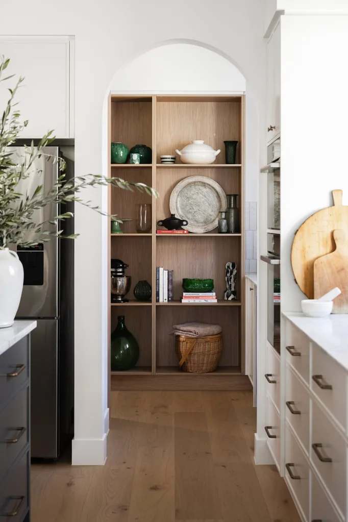 An arch leads from the kitchen to the timber shelving of the pantry. This arch is typical of Spanish mission-style.