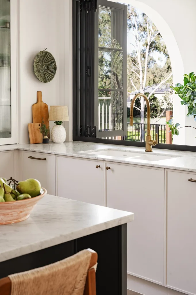 The window above the kitchen sink opens out to the exterior. A white arch is visible through the window, typical of Spanish mission-style.