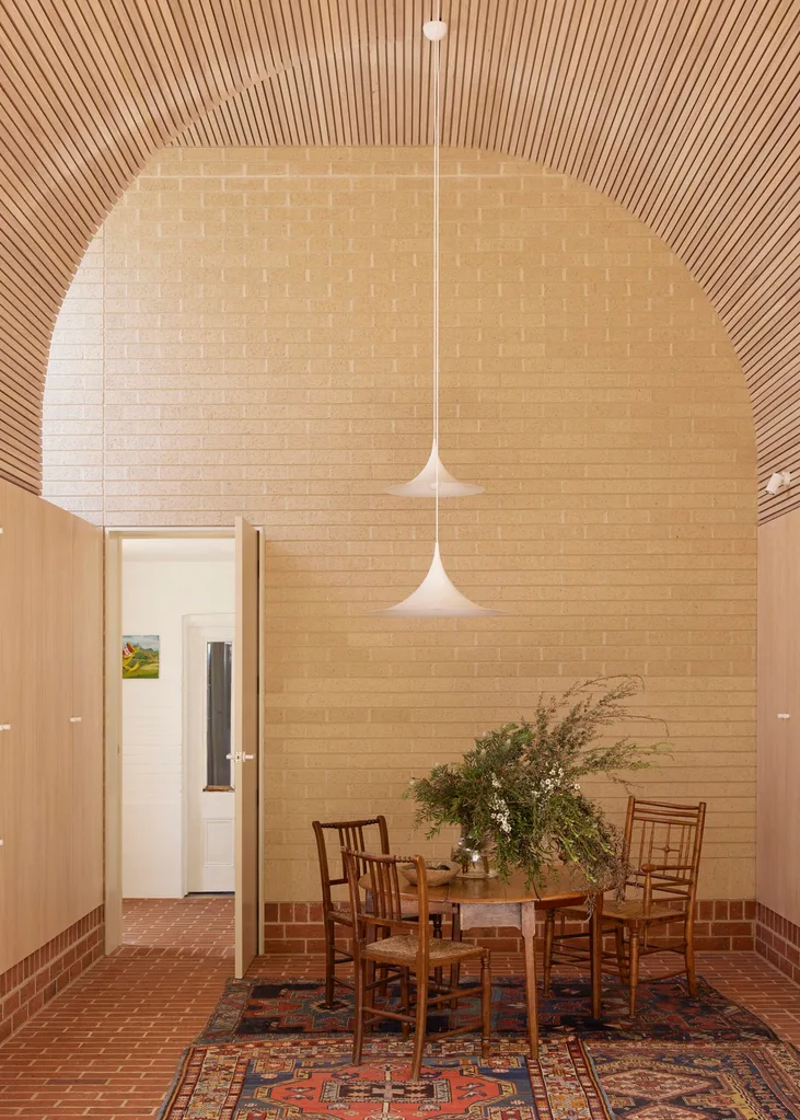 A brick room with a dining table and pendants lights.