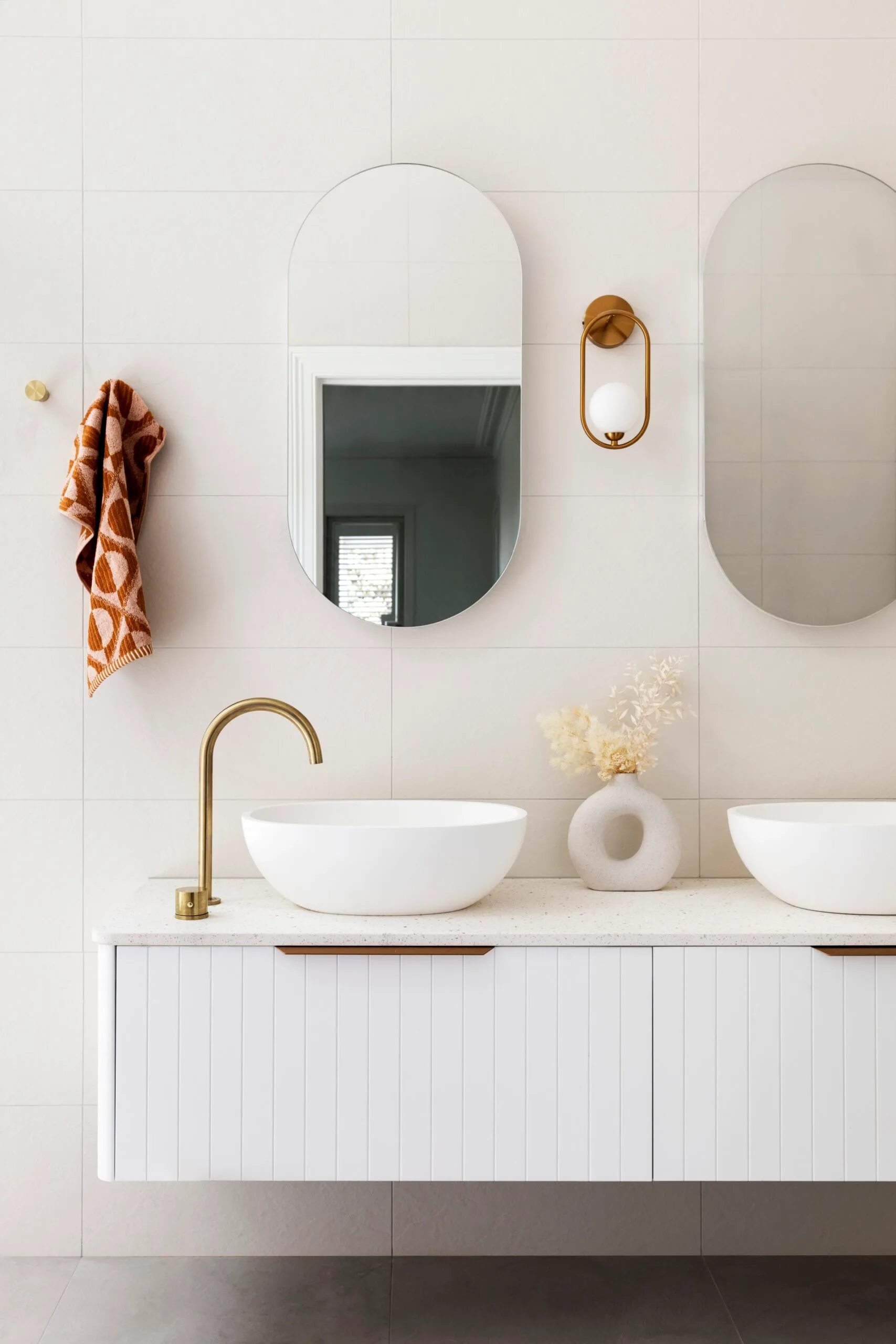 A double vanity with an orange patterned towel. 