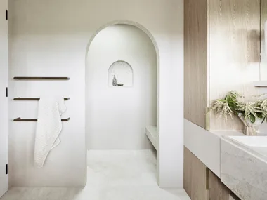 Earth tones fit in to the earthy colour palette in this bathroom. The floor tiles are raw-sawn limestone laid in a herringbone pattern. An arch leads from the vanity area to a sizable shower, complete with a shower bench made from honed quartzite.