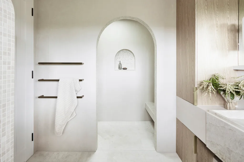 Earth tones fit in to the earthy colour palette in this bathroom. The floor tiles are raw-sawn limestone laid in a herringbone pattern. An arch leads from the vanity area to a sizable shower, complete with a shower bench made from honed quartzite.