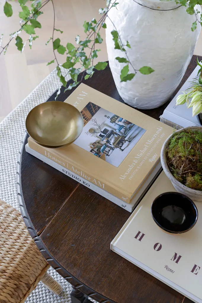Table with books, foliage and bowls arranged on top