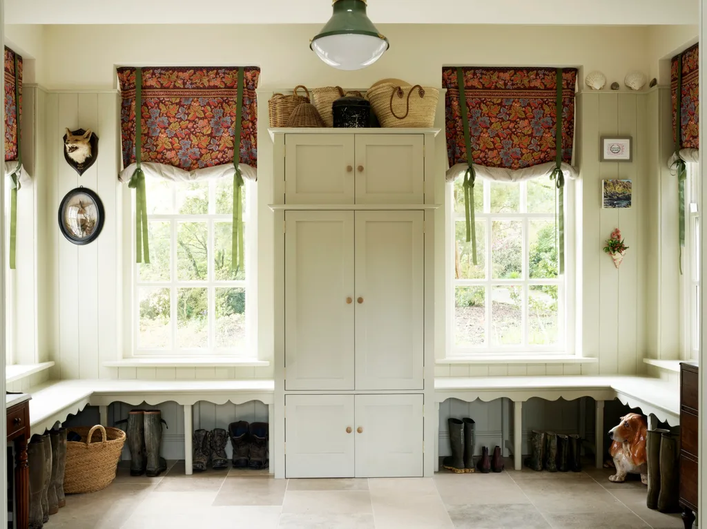 Bench seating lines this mudroom by Salvesen Graham, with boots stored beneath it. The VJ-panelled walls, banquette and cupboard are finished in the same soft hue, creating a cocooning effect that welcomes guests through this liminal space and into the home.