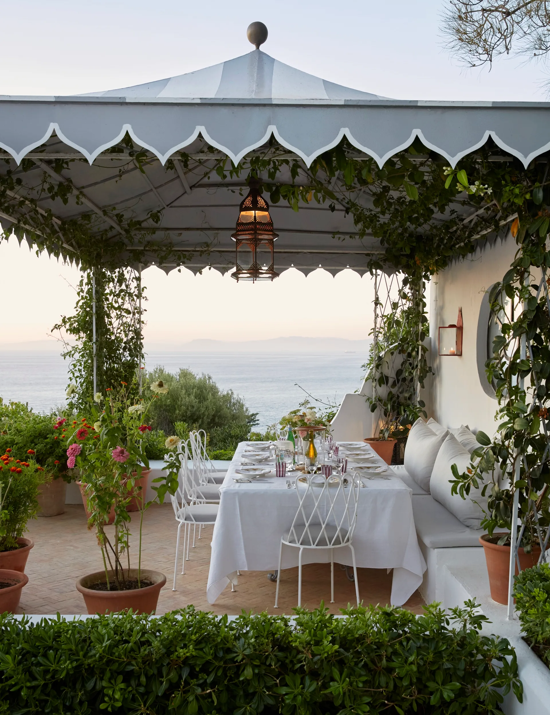 A gazebo, part of designer Veere Grenney’s home atop the
Old Mountain in Tangier, overlooks a lushly terraced garden.
Grenney designed the furniture for this Regency dining pavilion
in grey and white to echo the pavilion’s grey and white stripes.