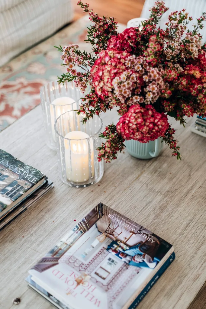 Coffee table decoration including coffee table books, candles and red flowers.