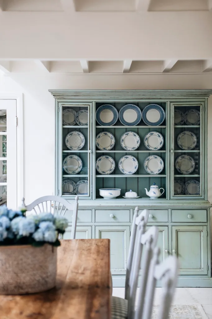 A china cabinet filled with plates in a beautiful Nantucket style home.
