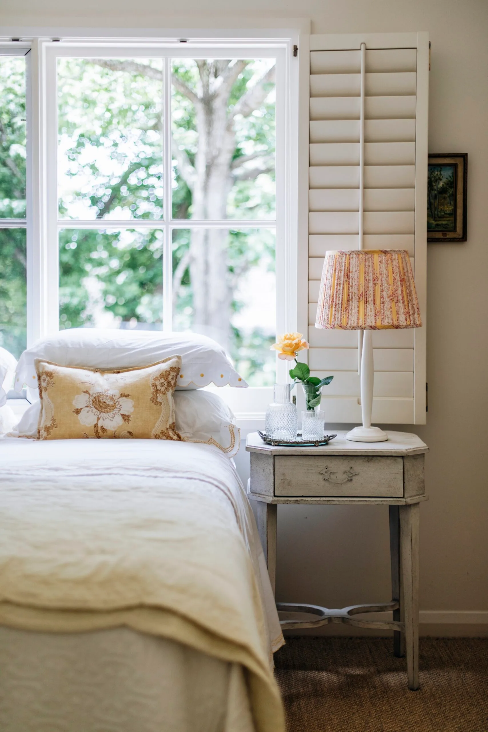 A bedroom with yellow cushions, lamp and bedspread. 