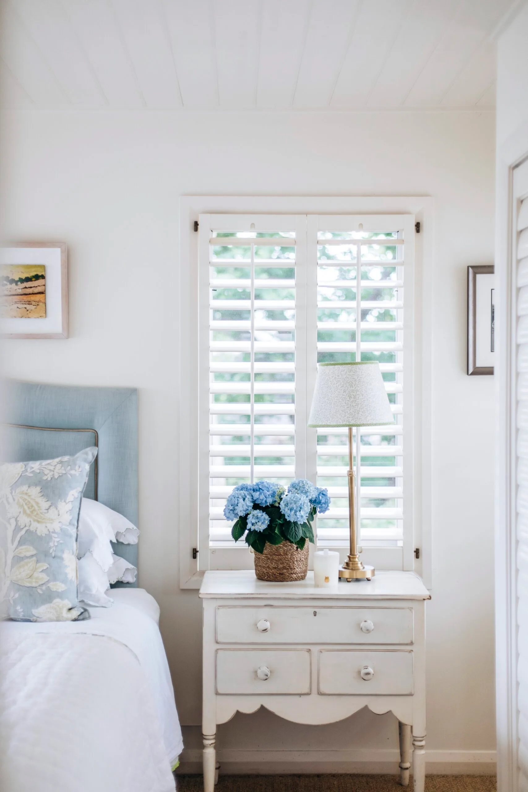 A blue bedroom with a French Provincial bedside table. 