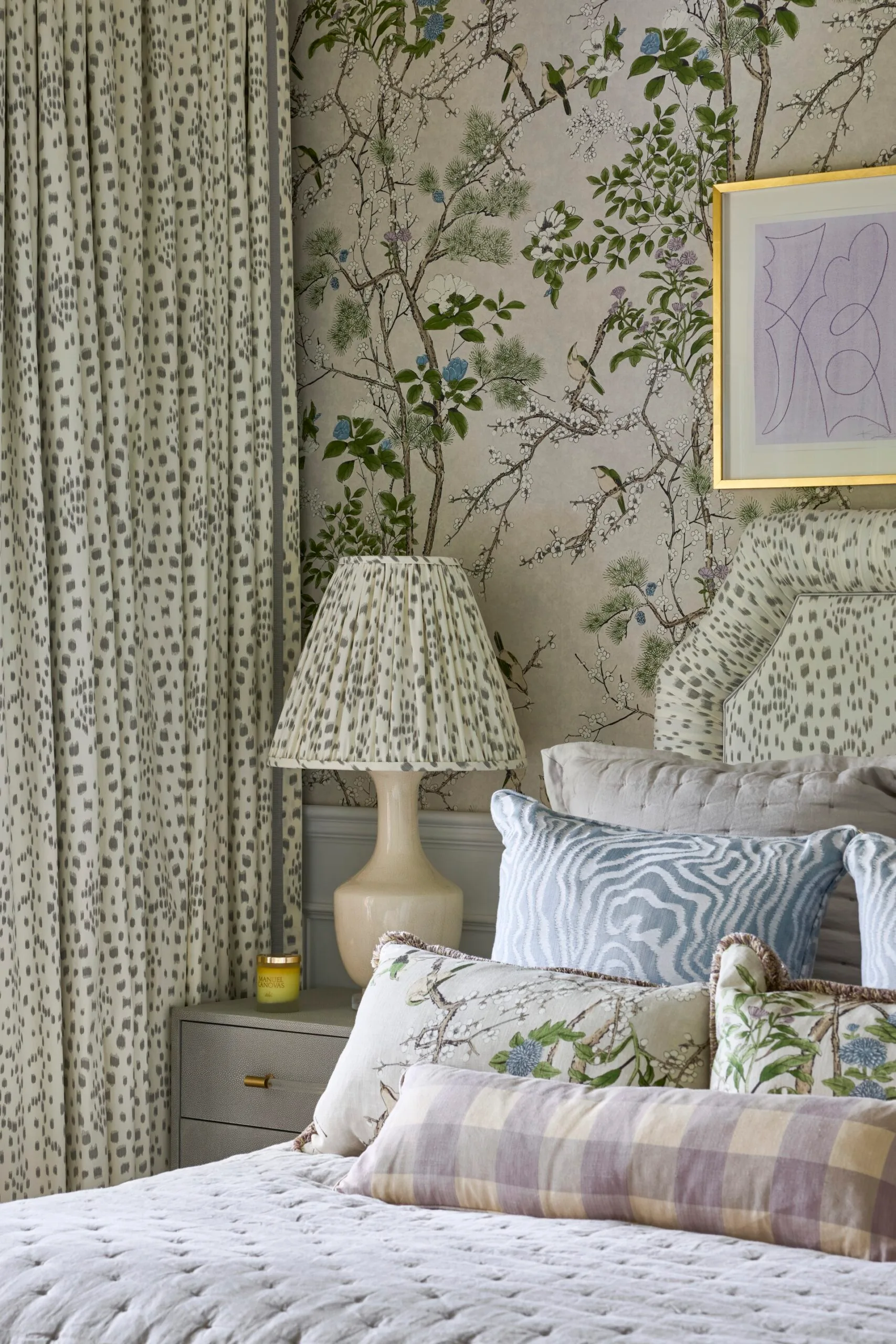 A bedroom with patterned wallpaper, curtains and cushions. 