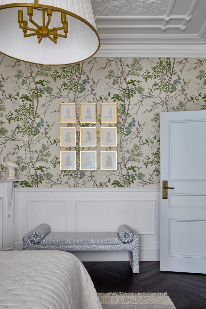 A bedroom with green patterned wallpaper and an upholstered bench seat.