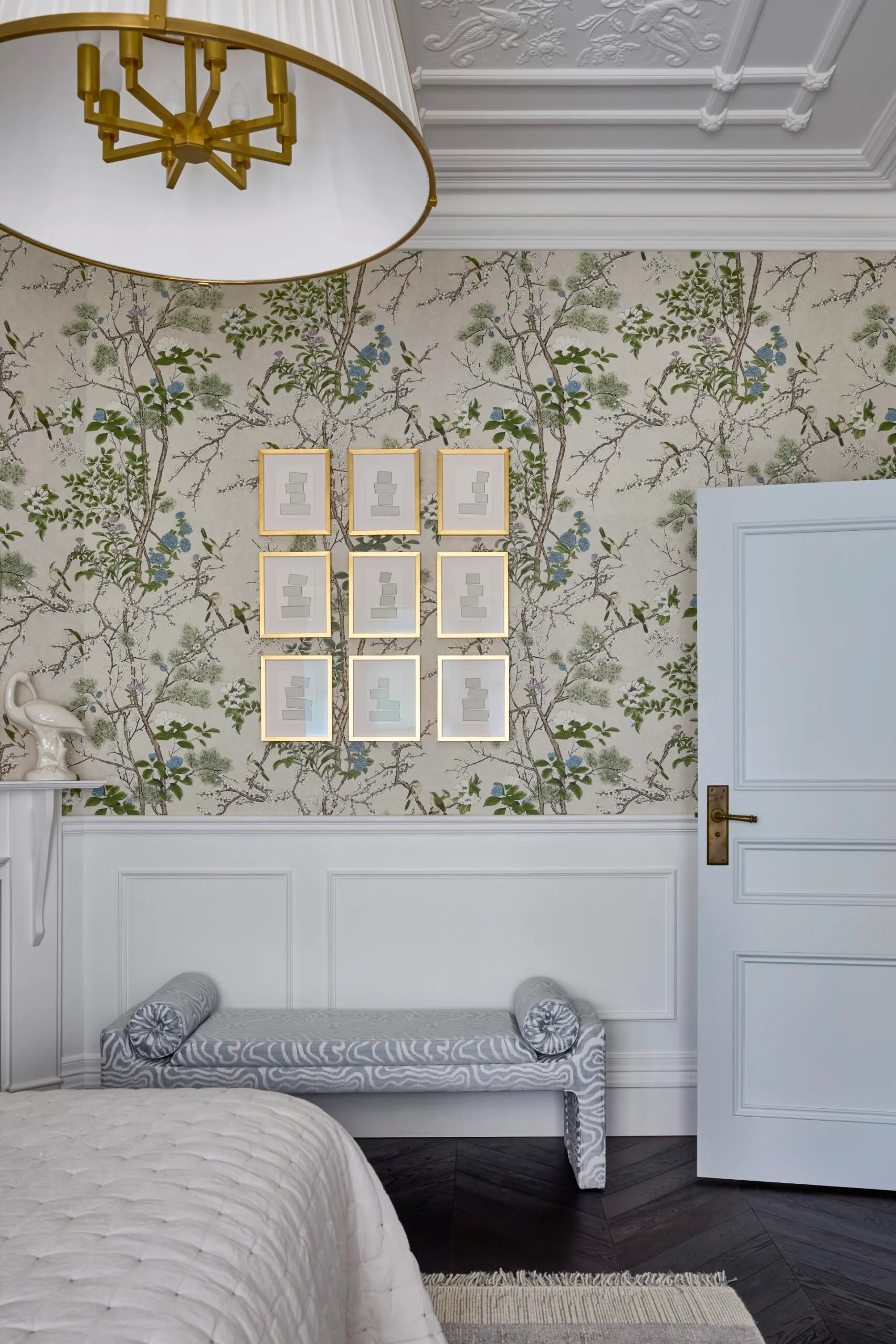 A bedroom with green patterned wallpaper and an upholstered bench seat. 