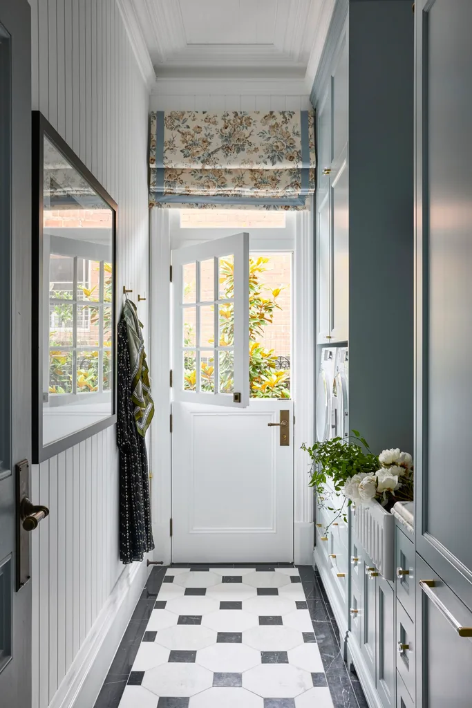 A laundry room with a tiled floor and patterned roman blinds.