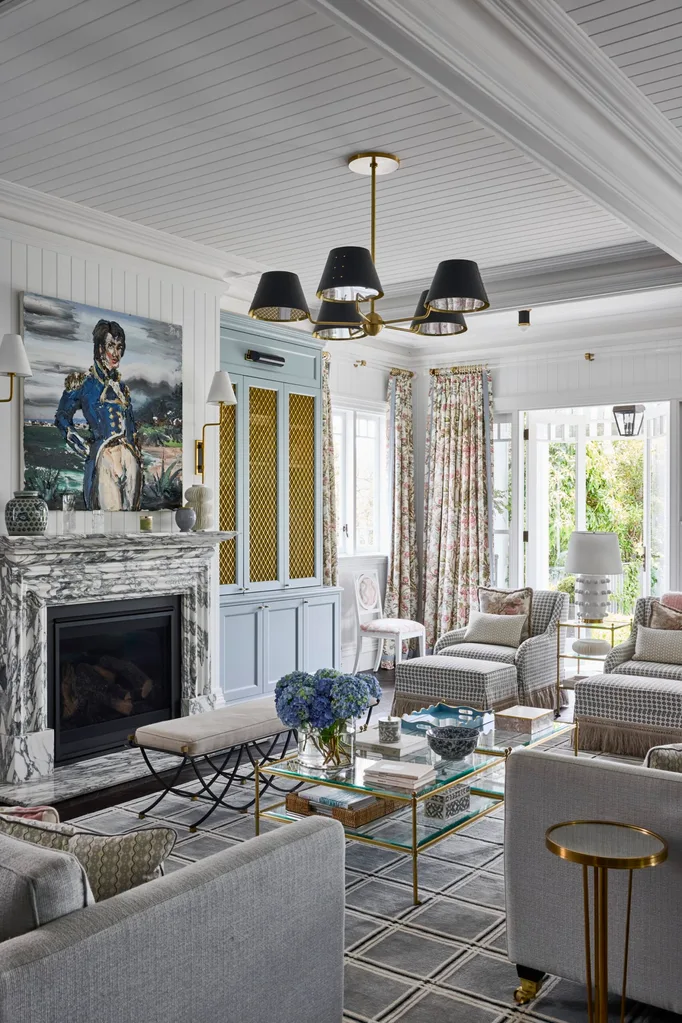 A comfortably furnished living room with a marble fireplace and soft grey furnishings.