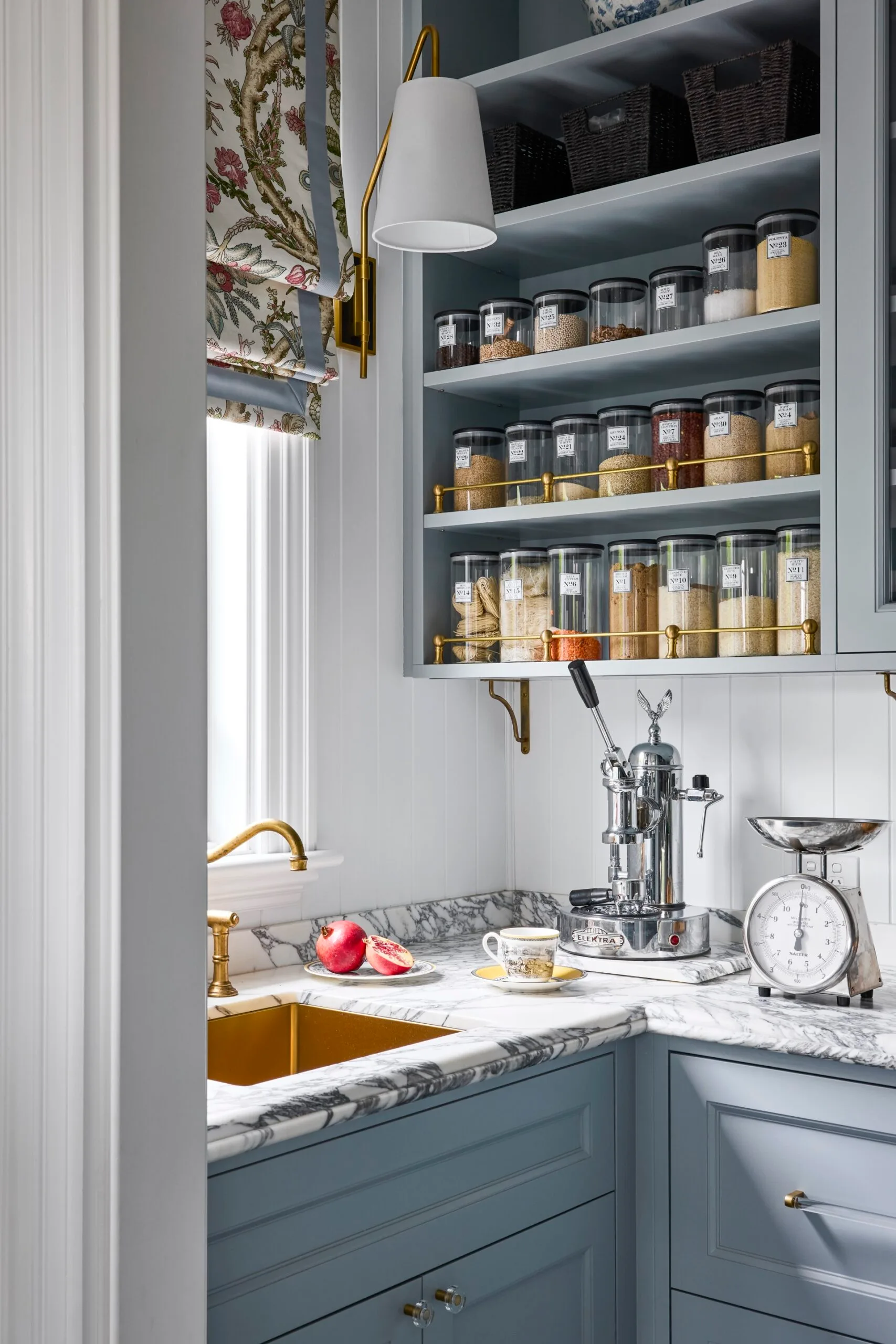 Pantry storage within a butler's pantry with a marble countertop and blue cabinetry. 