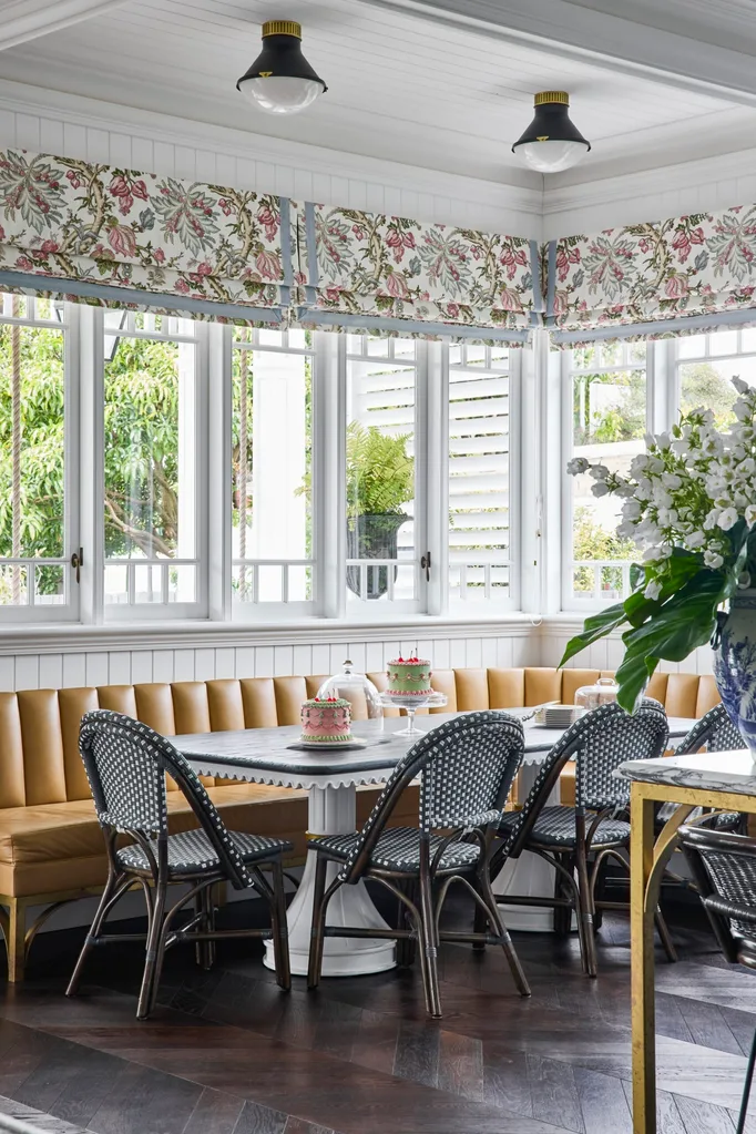 A dining nook with a yellow bench seat and patterned curtains.