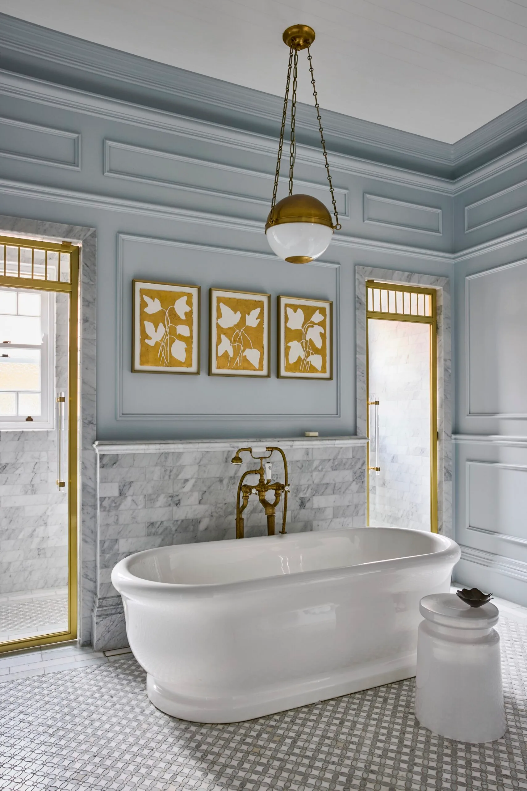 A pale blue bathroom with a deep freestanding bathtub. 
