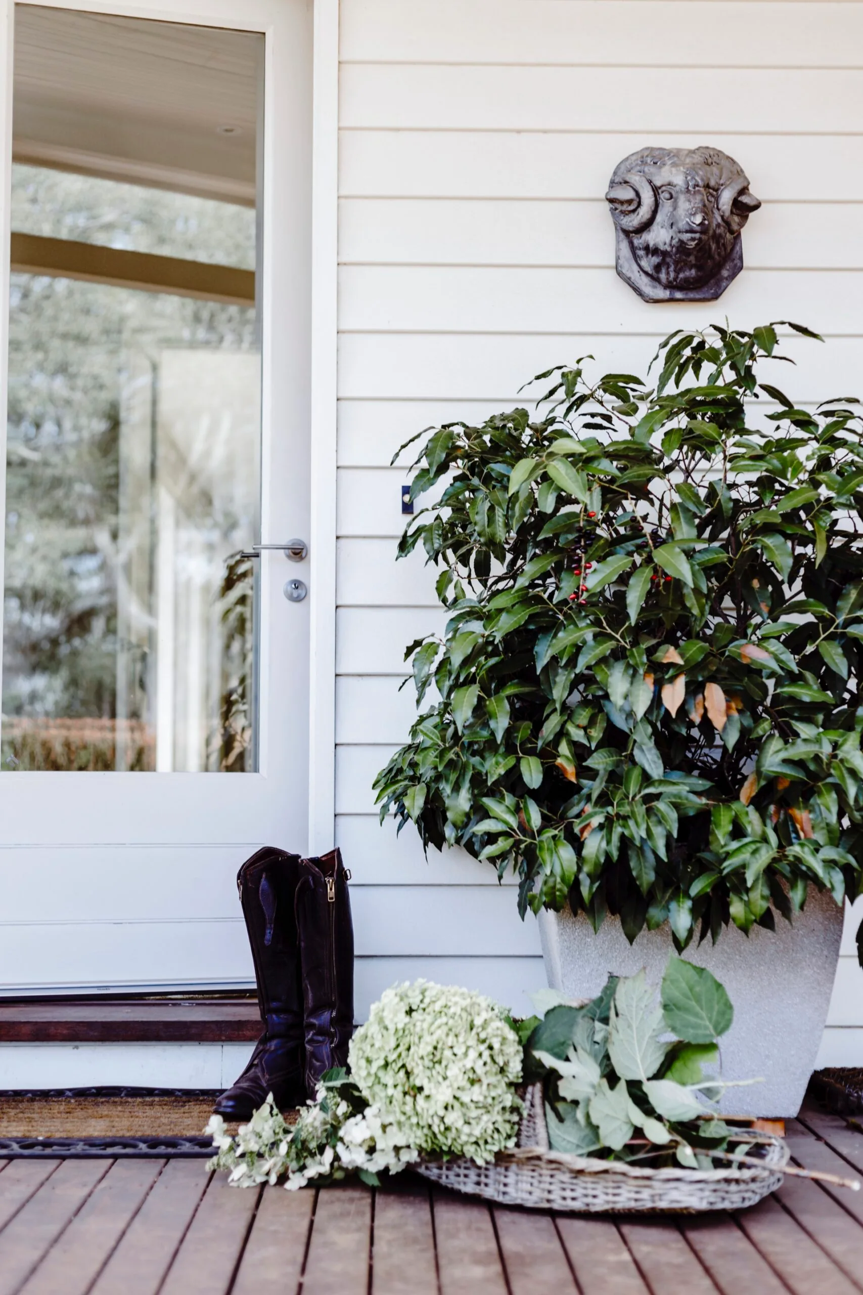 Boots and a basket of hydrangeas are placed at the entryway of this country home. 