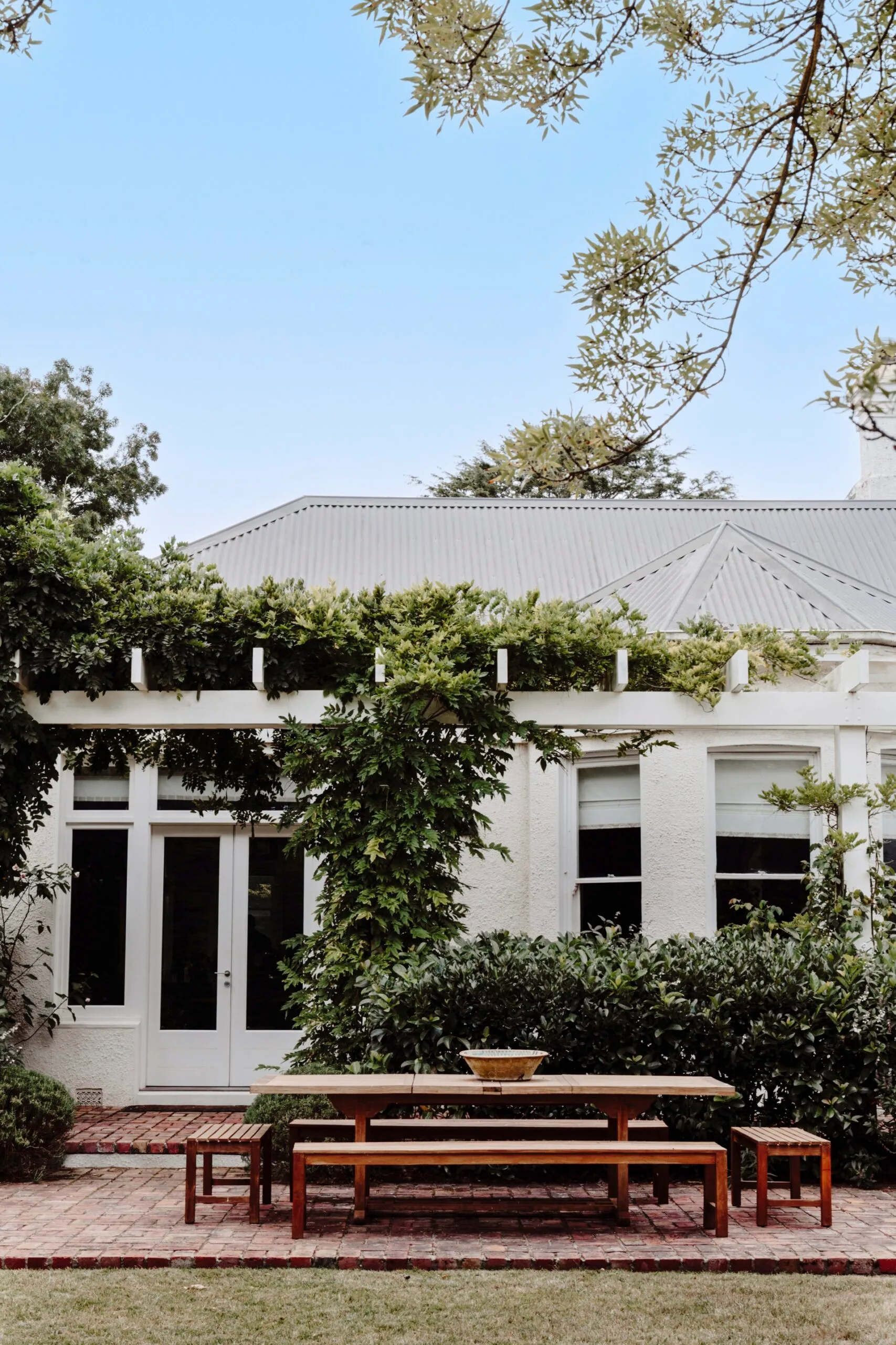 Climbing vines and a rustic outdoor table set the scene at this historic homestead. 