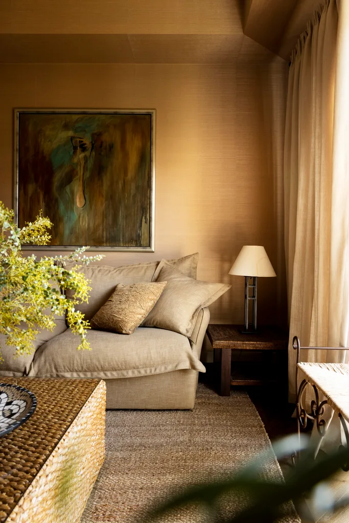 A warm-toned living space with a yellow wall, jute rug and linen sofa.