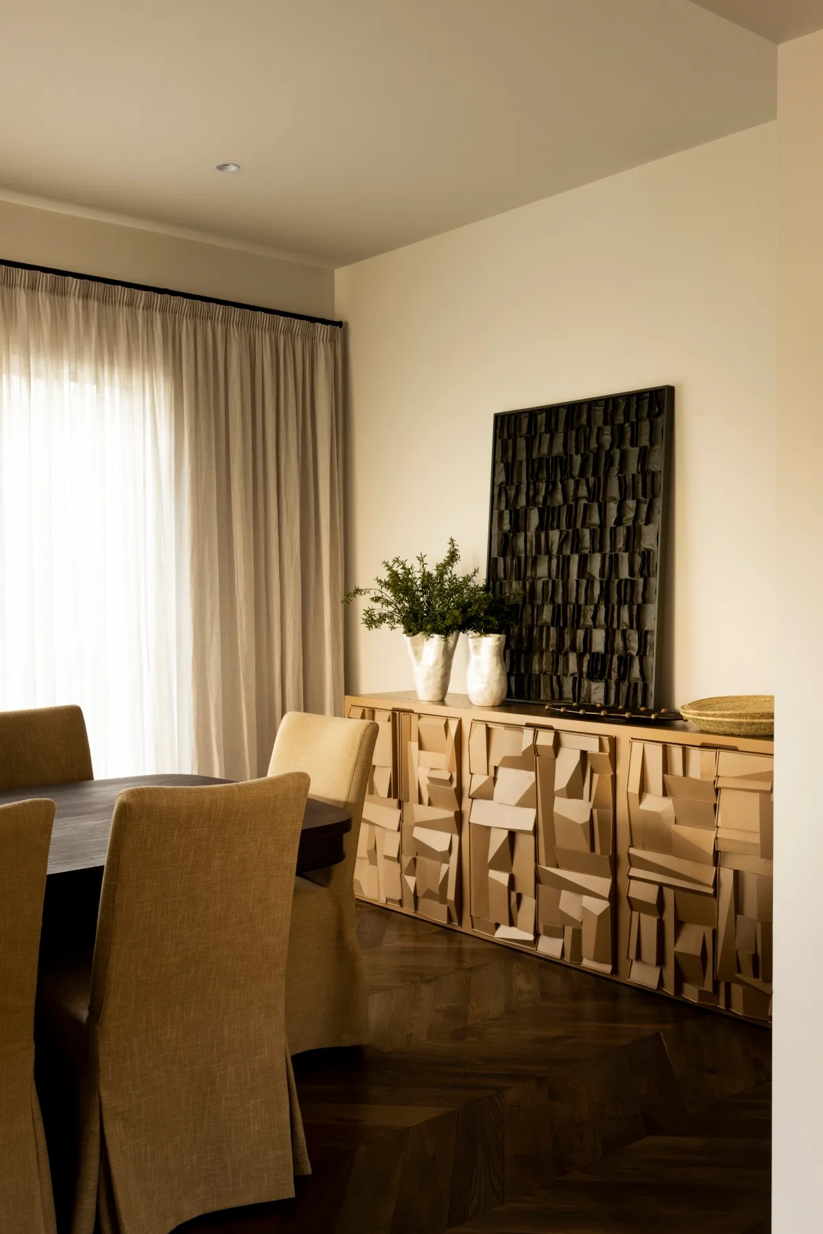 Warm textured dining room with upholstered seats amd a statement artwork. 